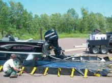 Inspecting and cleaning a boat to remove invasive plants and mollusks.